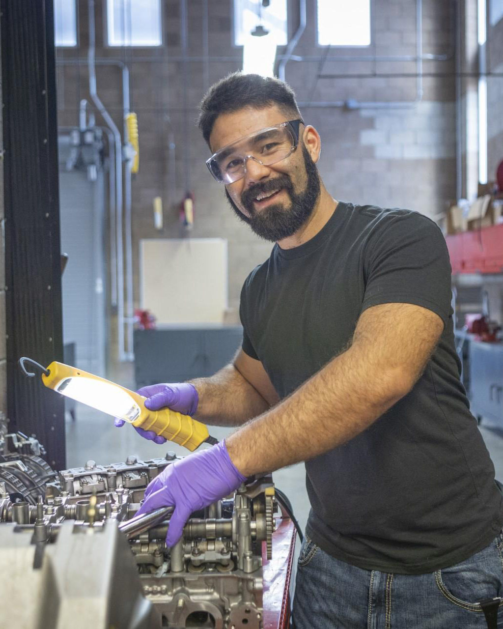 John Loewenberg holds a light over an engine and smiles at the camera