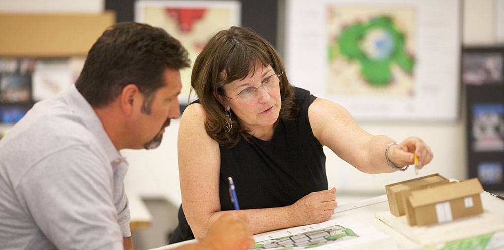 A teacher works with a student at a desk