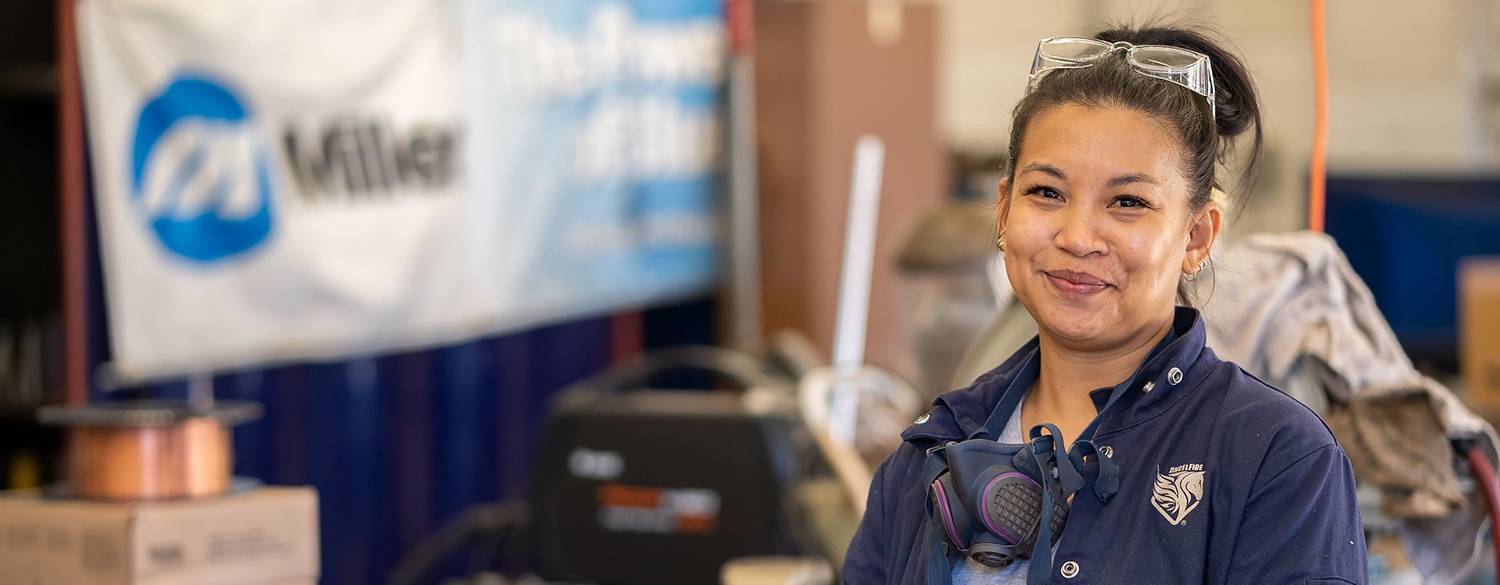 A student in a workshop wears safety goggles around her neck