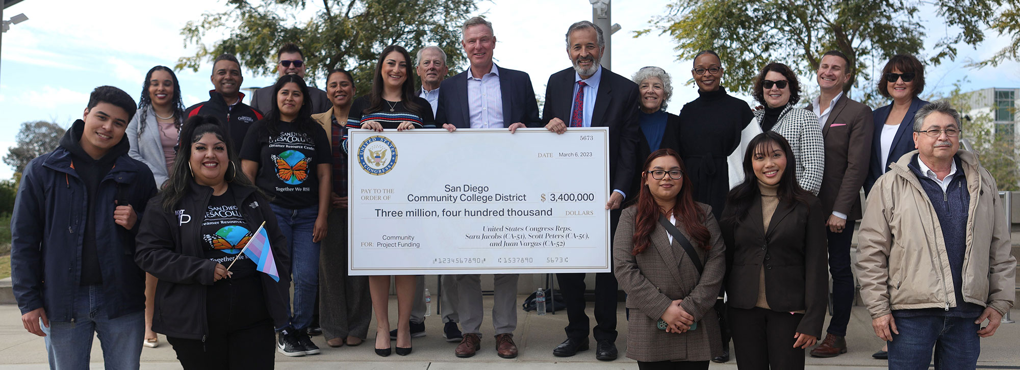 Three people holding a giant check for three point four million dollars