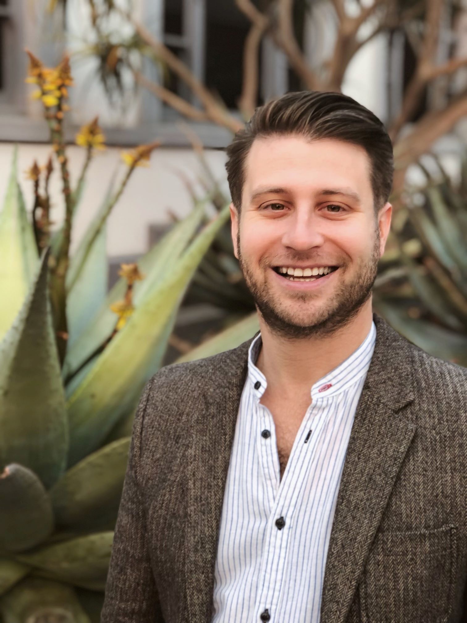 Matthew Ehrlich wearing a brown jacket and white shirt