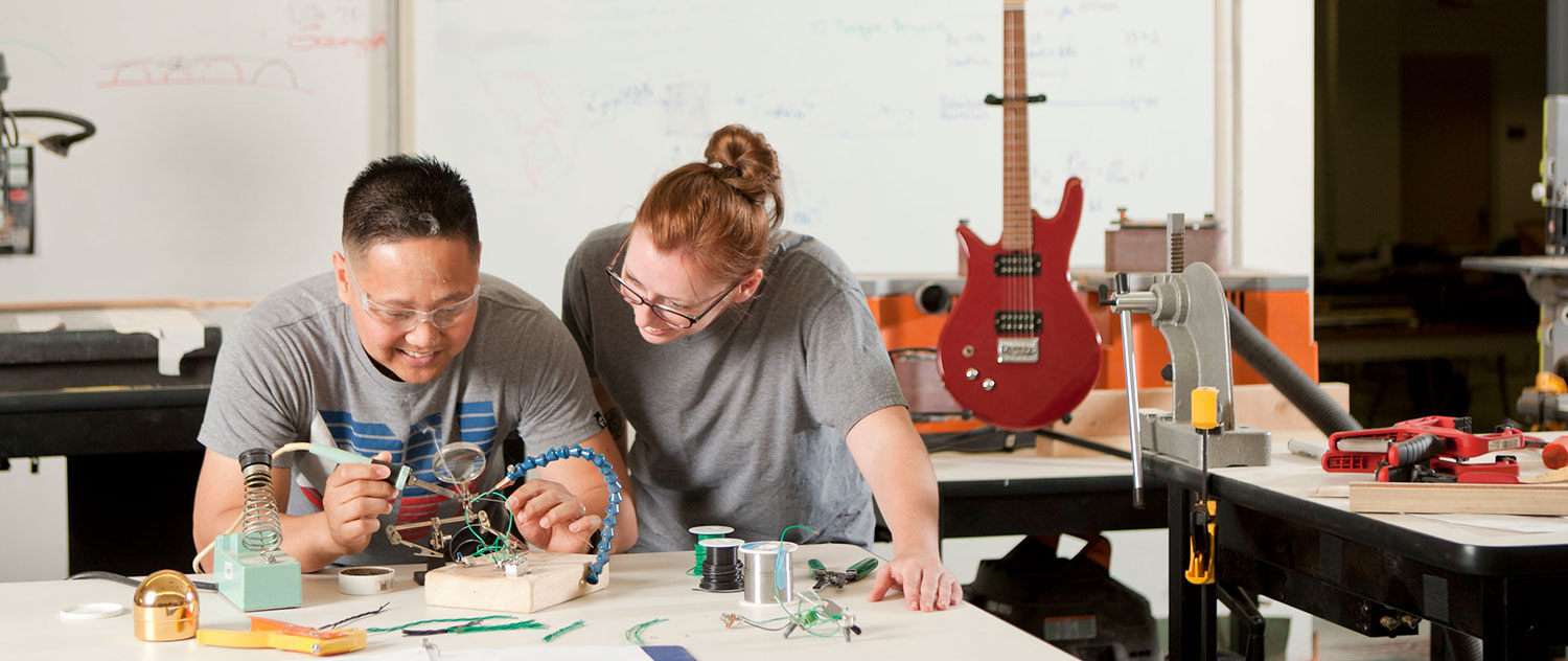 Two students at a work station in a guitar making class